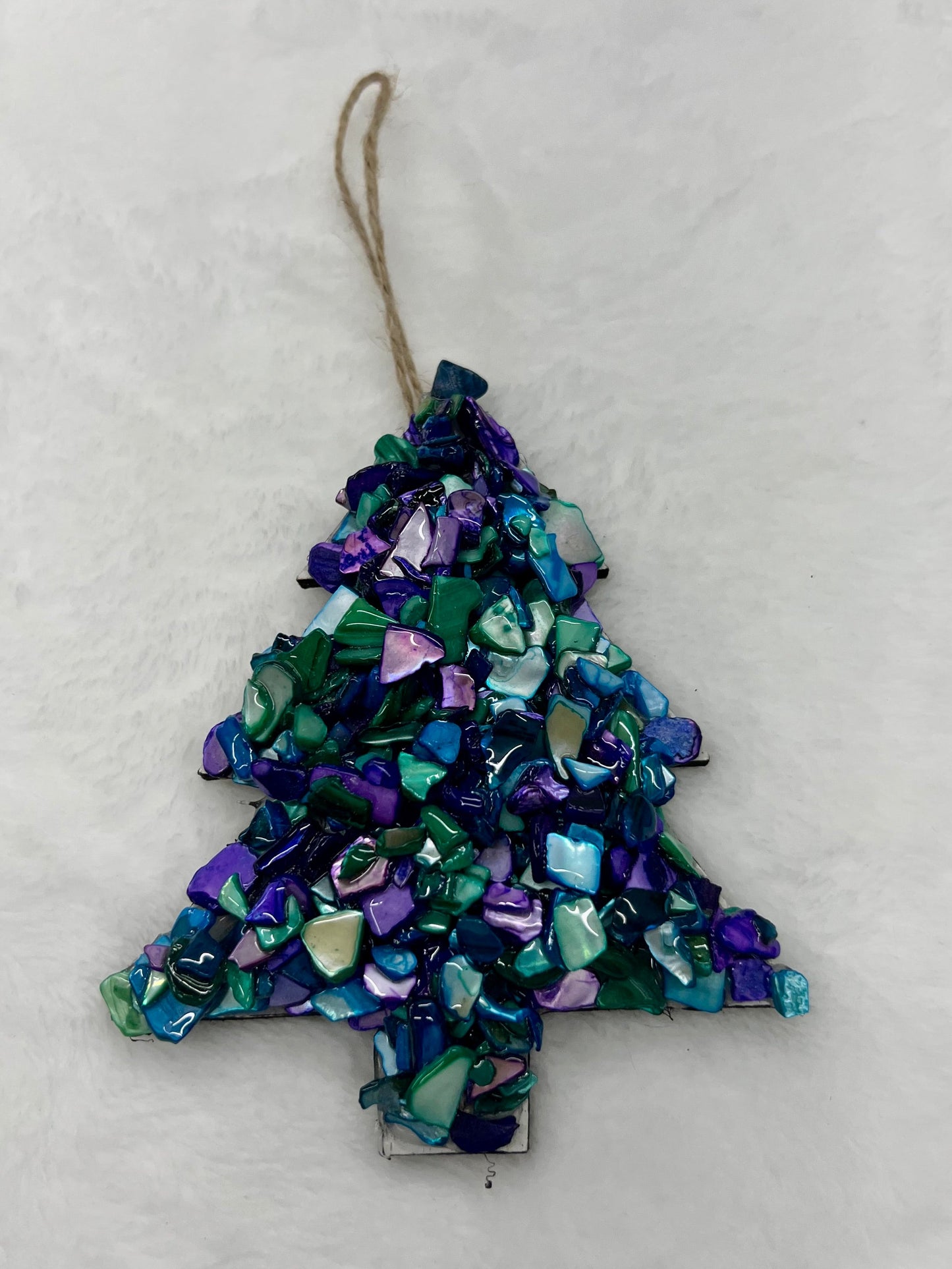 Decorative Christmas tree ornament with blue and green mosaic pattern on a white background
