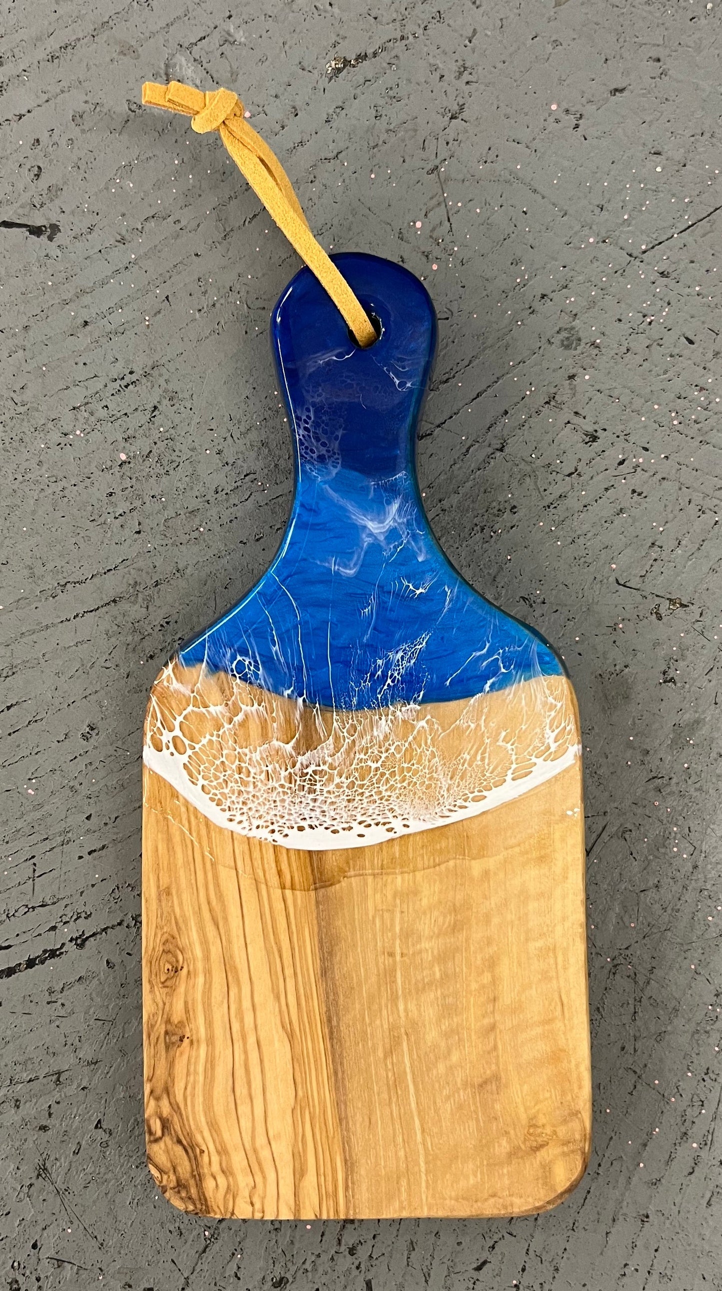 Wooden cutting board with blue and white design on a gray surface