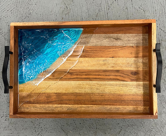 Wooden tray with a blue resin design on a gray textured background