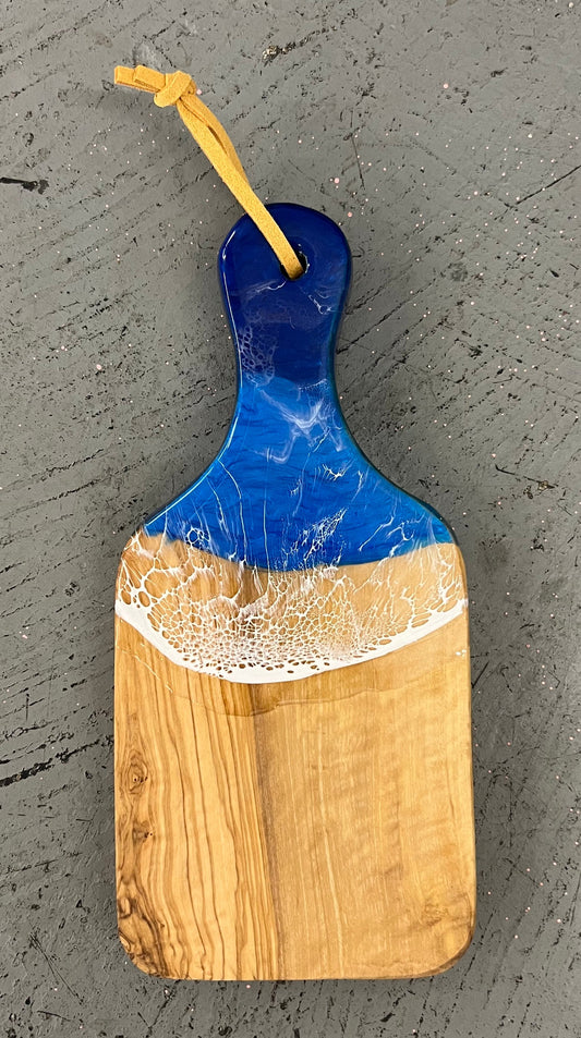 Wooden cutting board with blue and white design on a gray surface